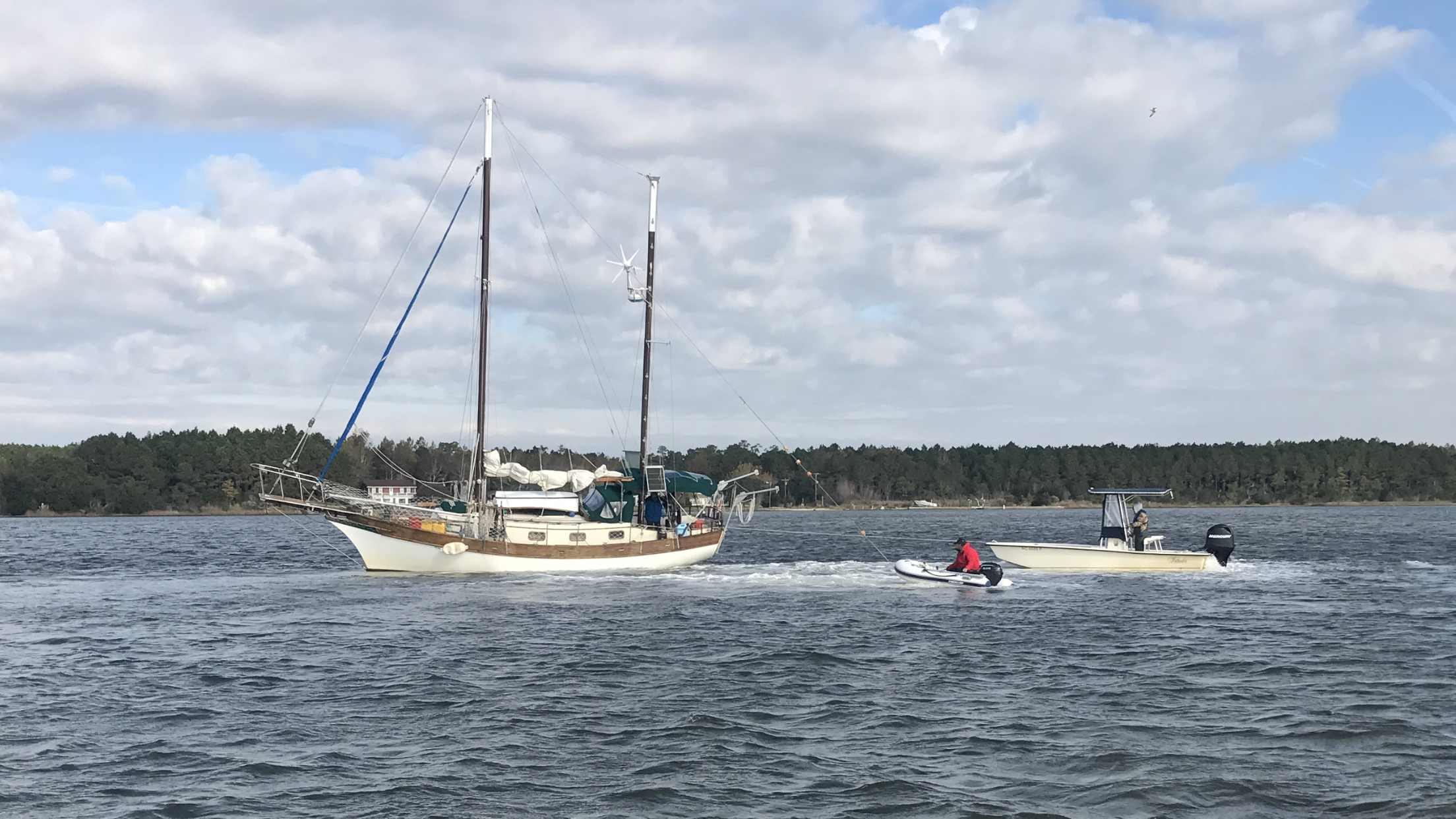A sailboat aground in the ICW. The Captain is in the dingy trying to pull the boat over to reduce its draft and free it.